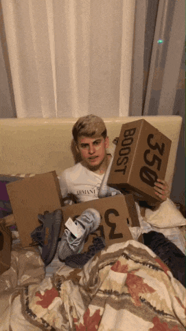 a man laying on a bed holding a box that says boost 350