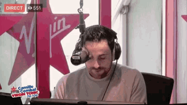 a man wearing headphones is sitting in front of a microphone and a virgin logo