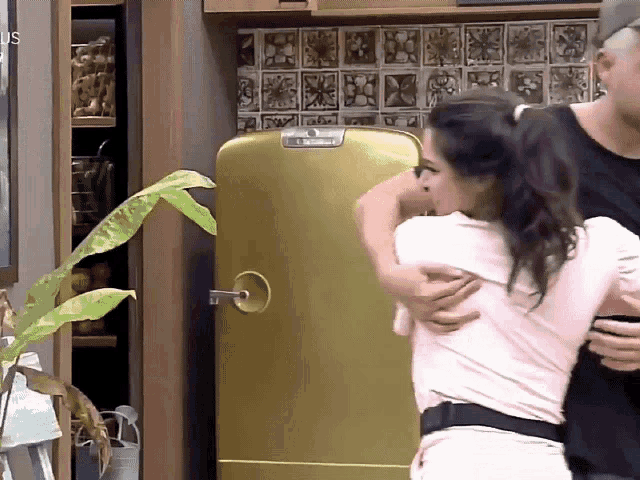 a man and woman are hugging in front of a yellow refrigerator