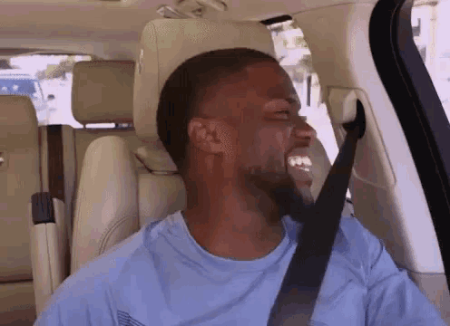 a man in a blue shirt is sitting in the back seat of a car with his seat belt on .