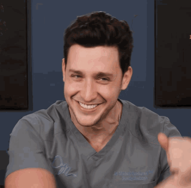 a smiling man wearing a scrub top that says ' dr. michael baumbaum ' on the front