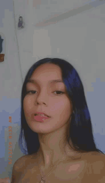 a girl with purple hair is taking a selfie with her phone .