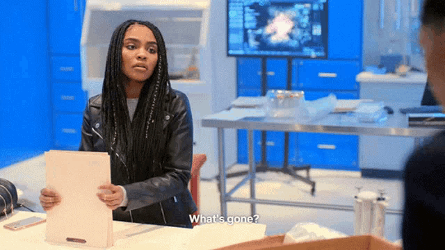 a woman sitting at a desk holding a piece of paper and asking what 's gone