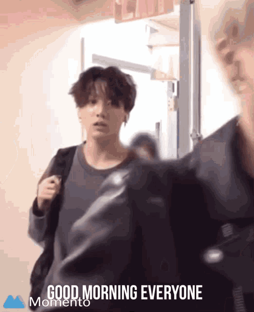 a man walking down a hallway with the words good morning everyone on the bottom