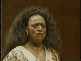 a woman with long hair is making a funny face while standing in front of a brown background .