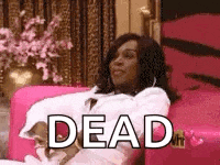 a woman is sitting on a pink couch with the words `` dead '' written on it .