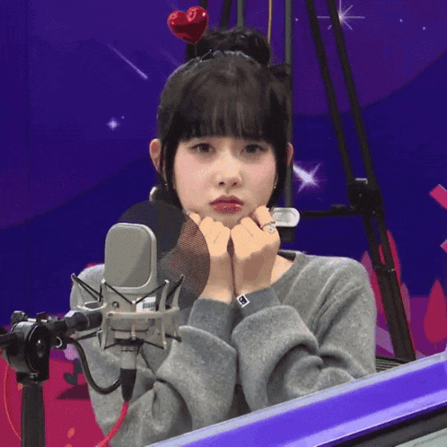 a girl wearing a headband with a red heart on it is standing in front of a microphone