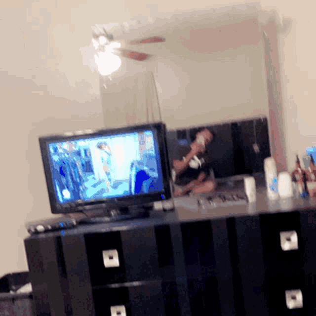 a man is sitting in front of a flat screen tv in a bedroom
