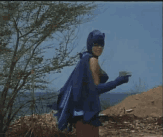 a woman in a bikini is dressed as batman and holding a bat
