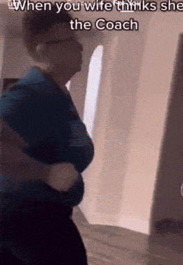 a man in a blue shirt is standing in a hallway with a caption that says when you wife thinks she is the coach