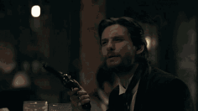 a man with a beard is sitting at a table in a dark room