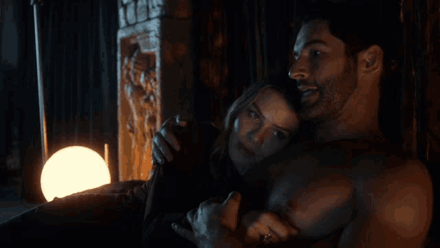 a man without a shirt is hugging a woman in the dark