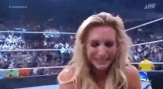 a woman is smiling in a wrestling ring with a crowd watching .