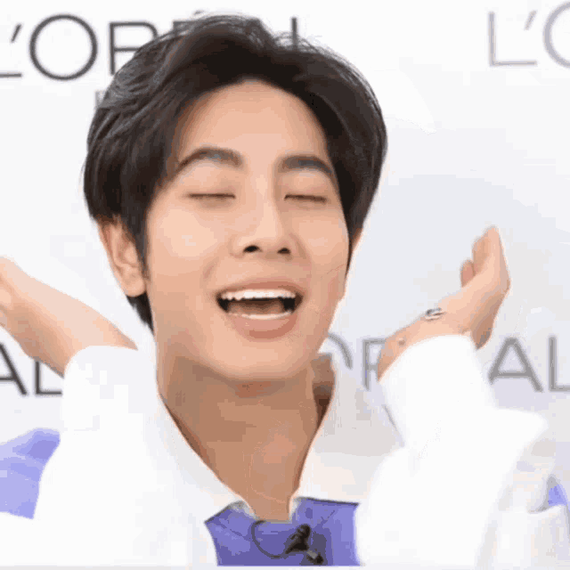 a young man is making a funny face in front of a sign that says l' oreal