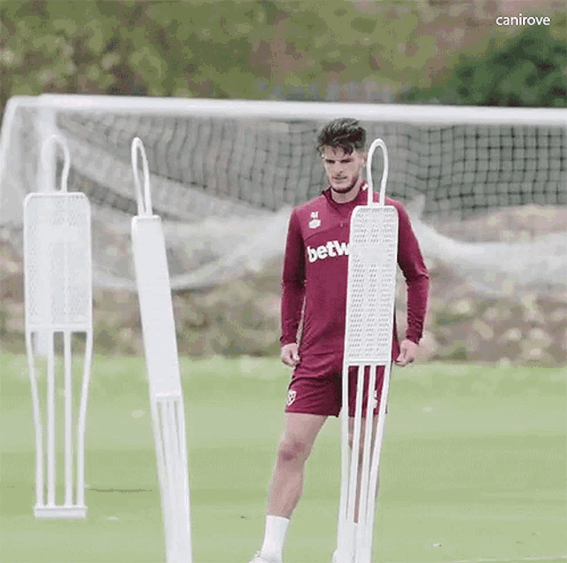 a soccer player wearing a betw jersey is standing next to a mannequin on a field .