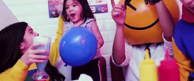 a group of people are sitting around a table with balloons .