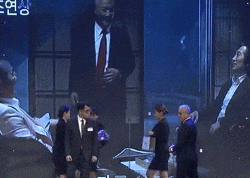 a man in a suit is standing in front of a large screen with a picture of a hand on it