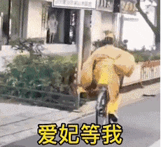 a man in a yellow suit is riding a bicycle down a street with chinese writing on it .
