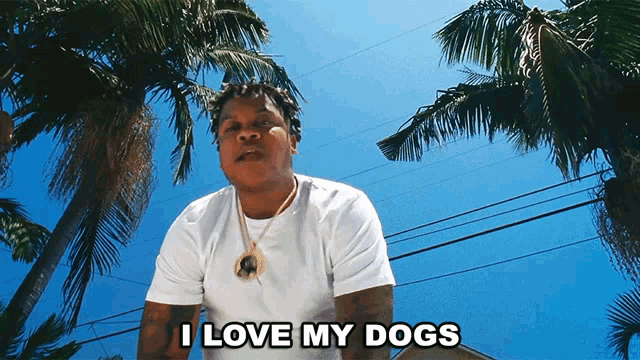 a man is standing in front of palm trees and says i love my dogs