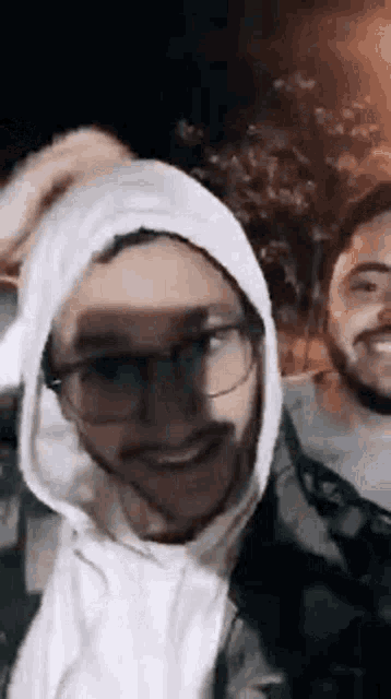 two men are posing for a picture together and one of them is wearing a hoodie .