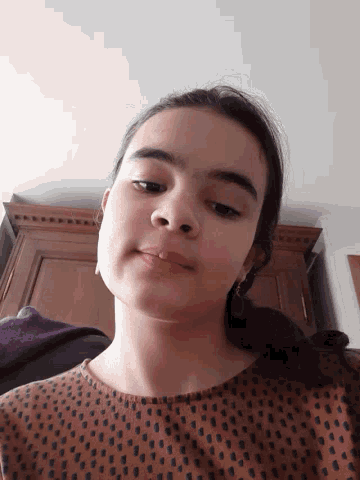 a close up of a girl 's face in front of a wooden cabinet