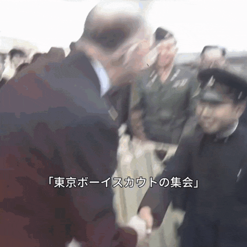 a man in a suit shakes hands with another man in a black uniform in a blurry photo with chinese writing