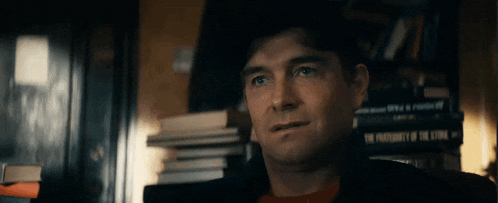 a man is sitting in front of a pile of books .