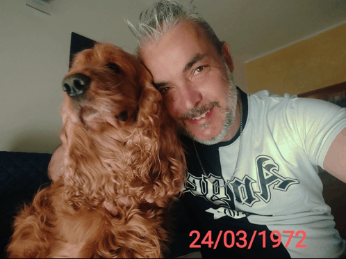 a man holding a dog wearing a shirt with the date 24/03/1972 on it