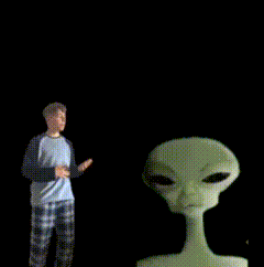 a man in plaid pajamas stands in front of a grey alien