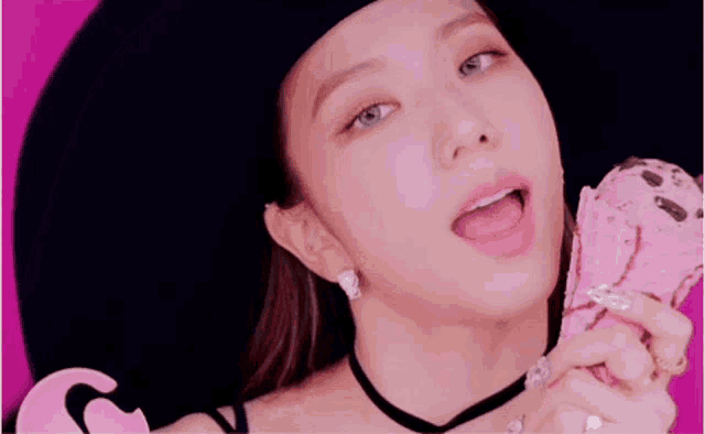 a close up of a woman holding a pink ice cream cone with her tongue out .
