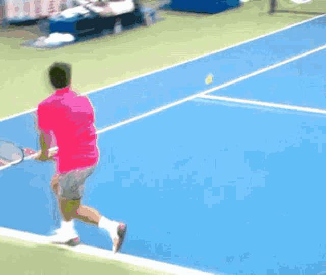 a man in a pink shirt is swinging a tennis racquet
