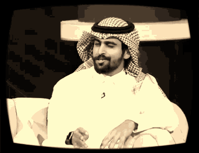 a man with a beard wearing a white shirt and a black and white head scarf