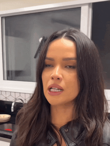 a woman in a black leather jacket is making a face