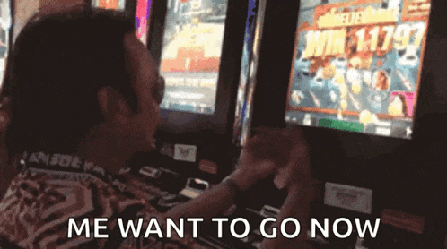 a man is playing a slot machine and says " me want to go now " .