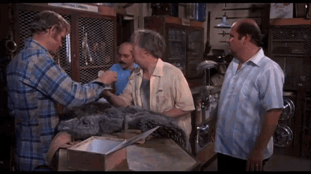 a group of men are standing around a table in a store talking