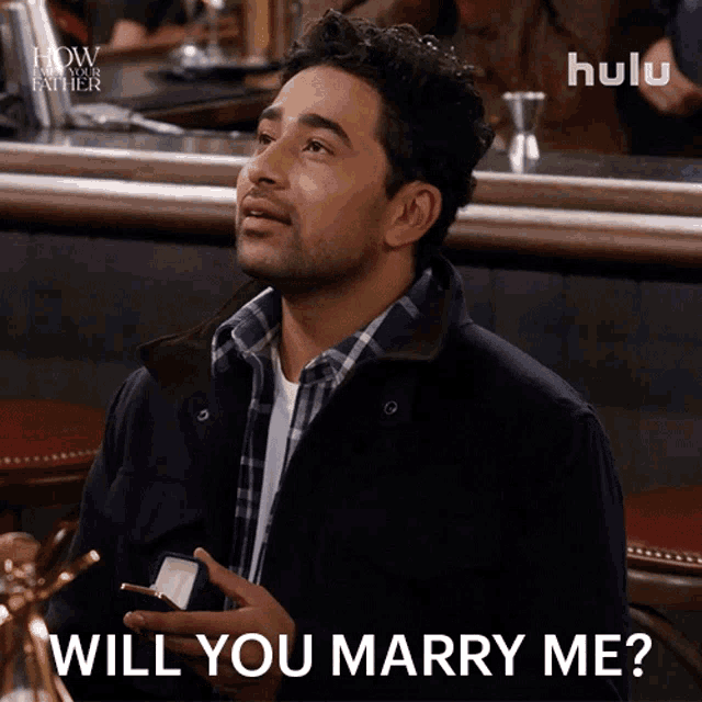 a man in a plaid shirt is holding a ring in his hand and says " will you marry me "