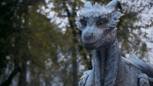 a statue of a dragon is standing in the woods with trees in the background