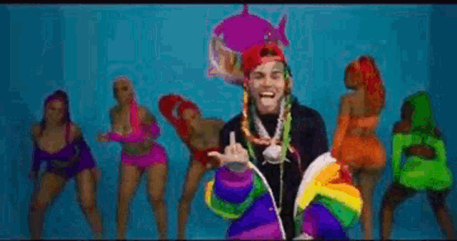 a man in a colorful costume is standing in front of a group of women dancing .