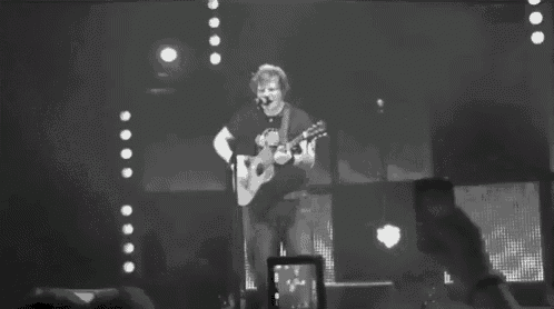 a man is singing into a microphone while holding a guitar on a stage .