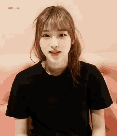 a girl wearing a black t-shirt is sitting on a pink couch .
