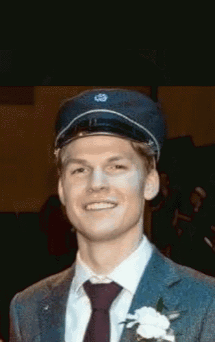 a man wearing a suit and tie is smiling and wearing a hat