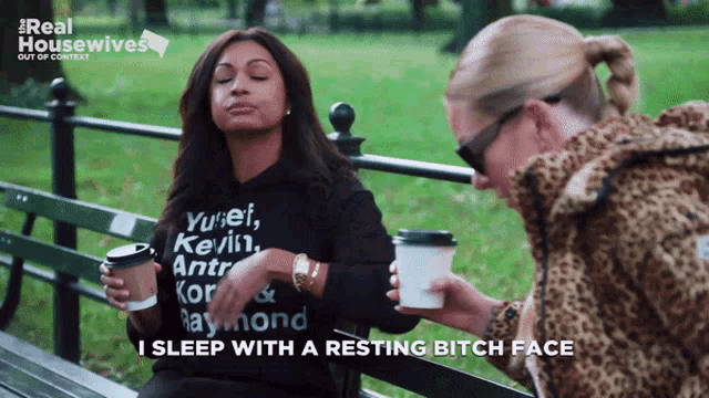 two women are sitting on a park bench and one of them is wearing a sweatshirt that says yunet