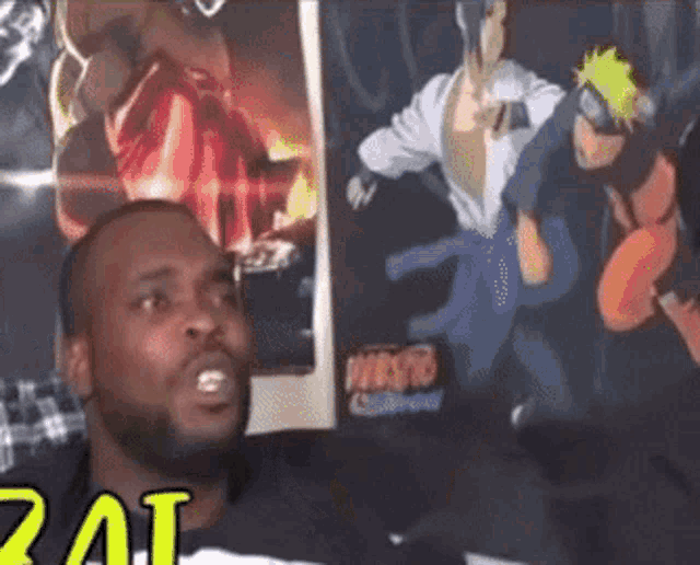 a man sitting in front of a poster of naruto