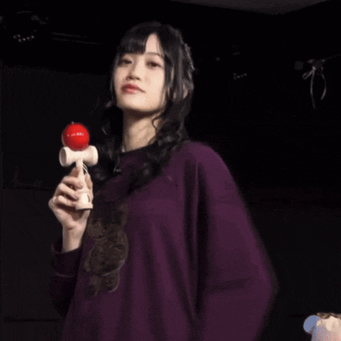 a woman in a purple shirt is holding a red ball