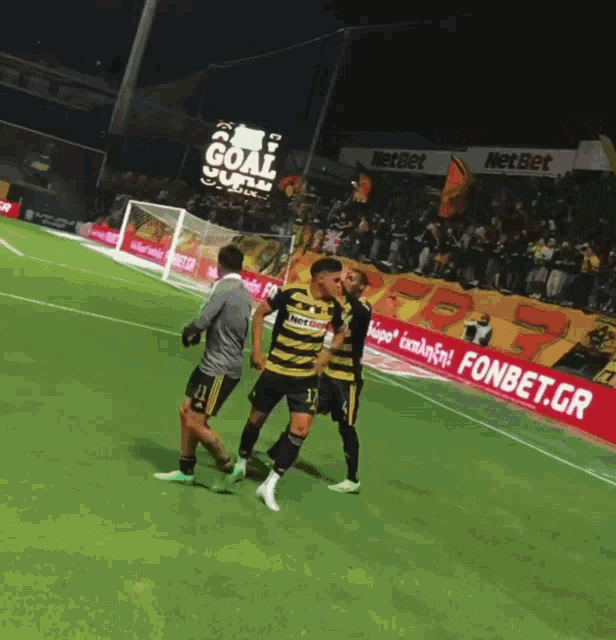 soccer players on a field with an ad for fonbet.gr in the background