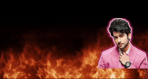 a man in a pink suit and tie is standing in front of flames