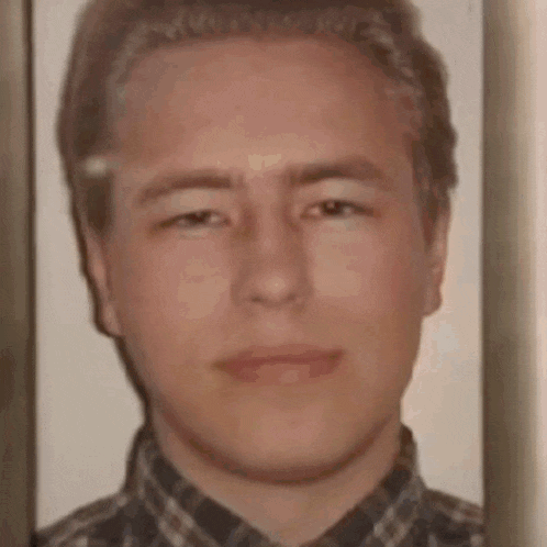 a man in a plaid shirt is looking at the camera .