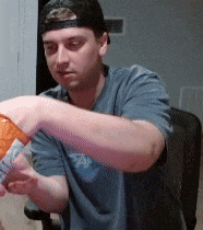 a man wearing a hat is holding a bag of chips in his hand