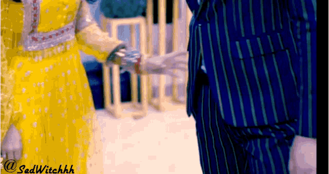 a man in a blue suit and a woman in a yellow dress are standing next to each other and holding hands .