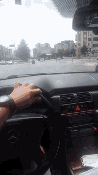 a person is driving a mercedes with a red light on the dash